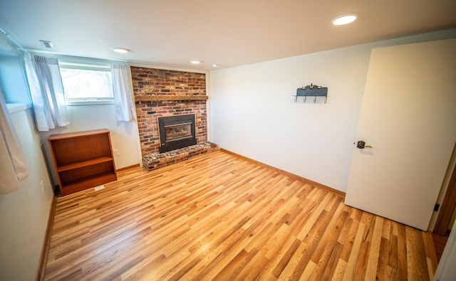 unfurnished living room featuring recessed lighting, a brick fireplace, baseboards, and wood finished floors