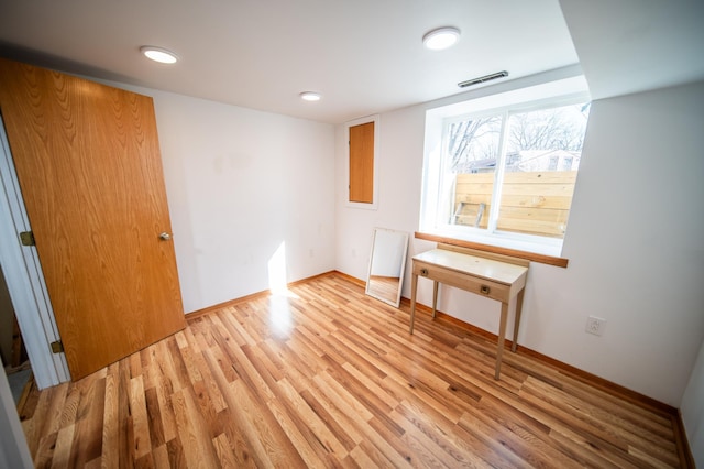 unfurnished room with light wood-type flooring, visible vents, and baseboards