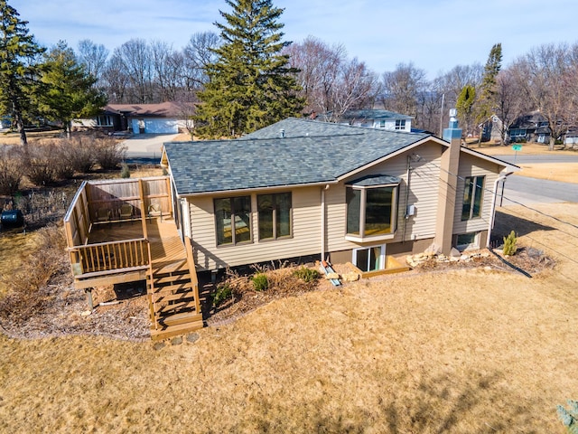 back of house featuring a wooden deck, roof with shingles, and fence