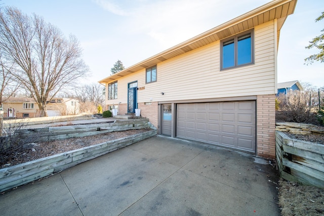 view of front of property featuring driveway, brick siding, and an attached garage