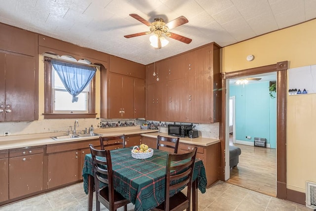 kitchen featuring tasteful backsplash, ceiling fan, sink, and light wood-type flooring