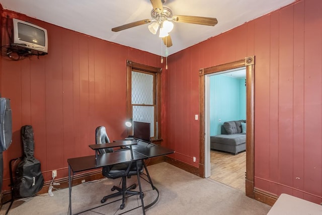 office area with ceiling fan, wood walls, and hardwood / wood-style flooring