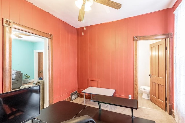 office featuring ceiling fan and wood walls