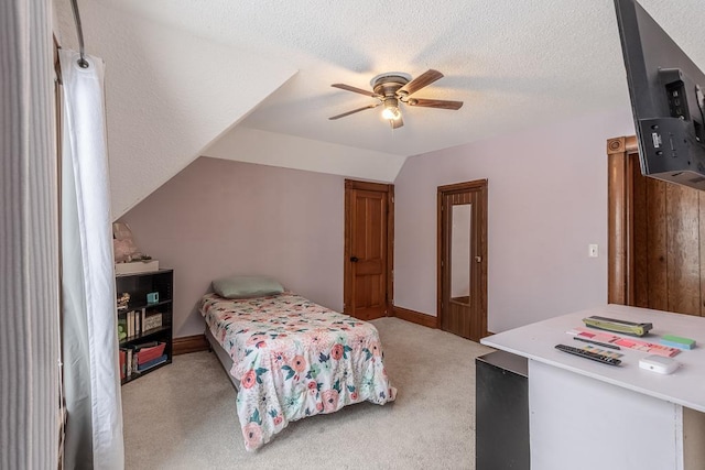 bedroom with a textured ceiling, light colored carpet, vaulted ceiling, and ceiling fan