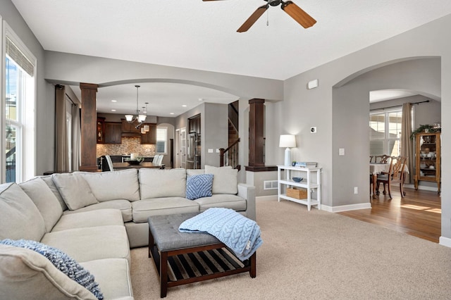 living room with ceiling fan with notable chandelier, plenty of natural light, and light carpet