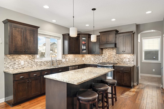 kitchen with appliances with stainless steel finishes, a center island, sink, and dark brown cabinets