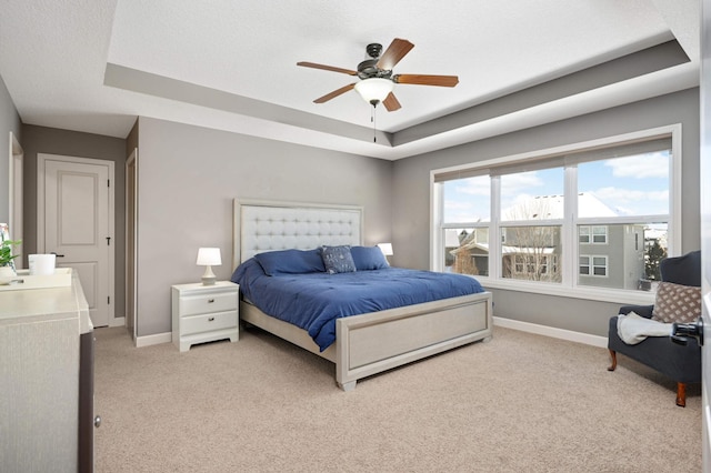 bedroom with ceiling fan, a raised ceiling, light carpet, and a textured ceiling