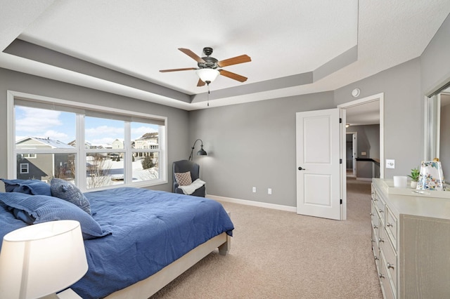 bedroom with ceiling fan, light colored carpet, and a raised ceiling