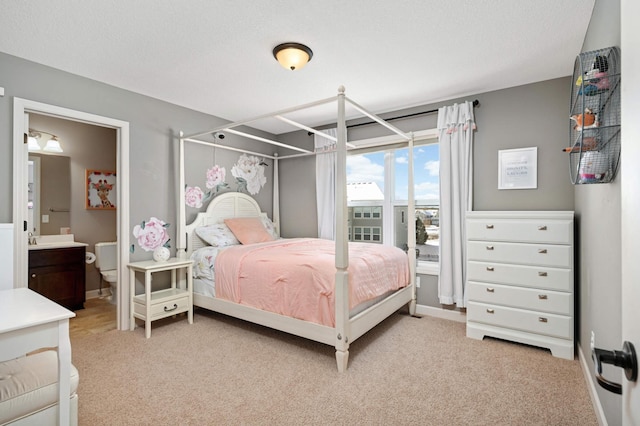 carpeted bedroom with ensuite bath and a textured ceiling