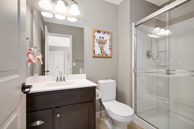 bathroom featuring vanity, a shower with door, and toilet