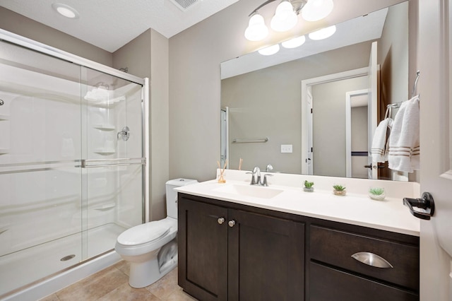 bathroom featuring a shower with door, vanity, tile patterned floors, and toilet