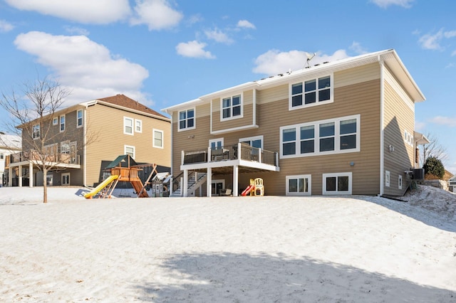 snow covered house with central air condition unit and a playground