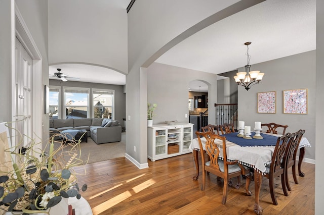 dining space featuring baseboards, arched walkways, and wood finished floors