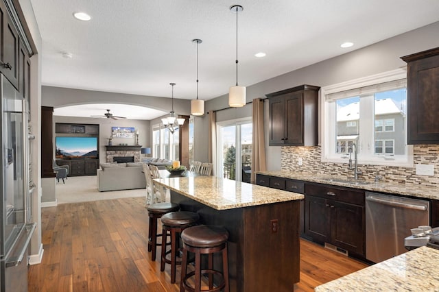 kitchen featuring dark brown cabinets, appliances with stainless steel finishes, a fireplace, and a sink