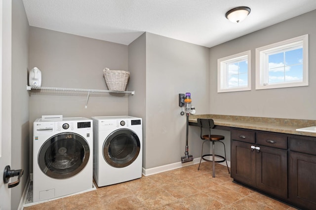 clothes washing area featuring baseboards, cabinet space, a textured ceiling, and washing machine and clothes dryer