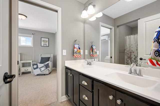 full bathroom with double vanity, a wall unit AC, a sink, and baseboards