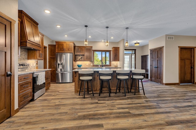 kitchen with a center island, hardwood / wood-style flooring, decorative backsplash, decorative light fixtures, and stainless steel appliances