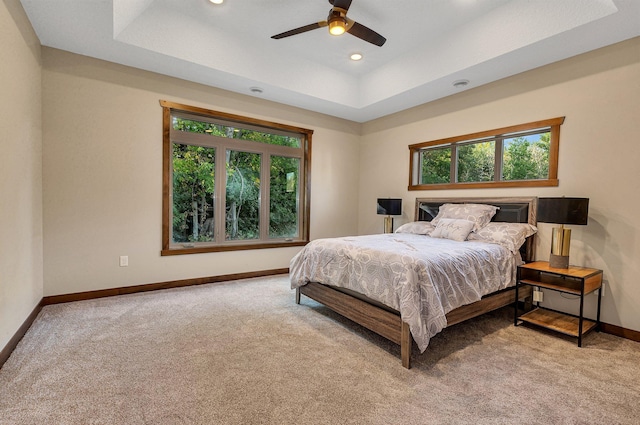 bedroom with a tray ceiling, ceiling fan, and light carpet