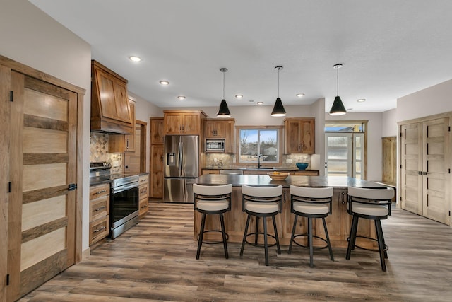 kitchen featuring a kitchen island, decorative backsplash, dark wood-style flooring, appliances with stainless steel finishes, and a sink