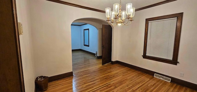 interior space with hardwood / wood-style flooring, crown molding, and an inviting chandelier