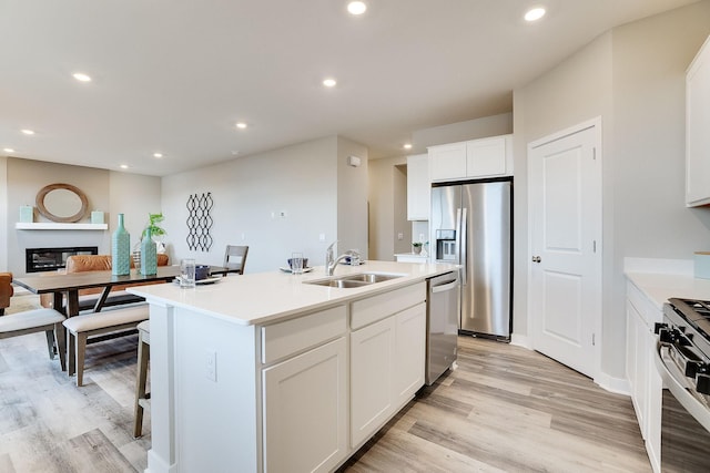 kitchen with white cabinets, sink, stainless steel appliances, and a kitchen island with sink