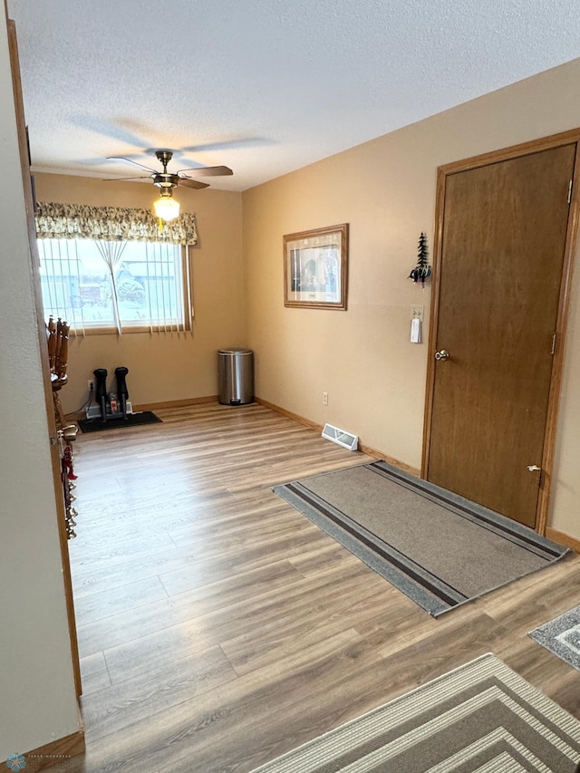 interior space featuring a textured ceiling, light hardwood / wood-style floors, and ceiling fan