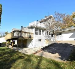 rear view of house featuring a wooden deck, a sunroom, a yard, and a patio area