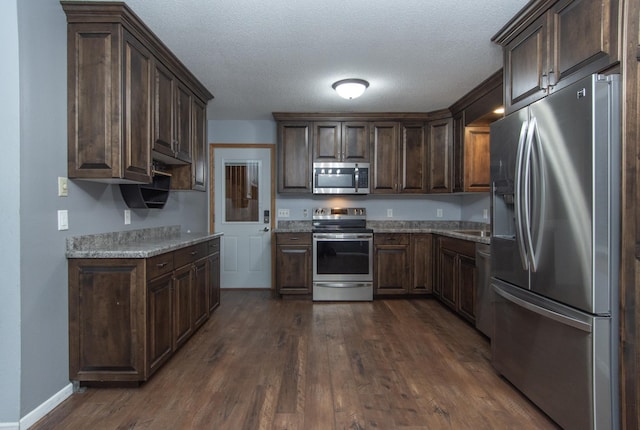 kitchen with dark brown cabinets, a textured ceiling, and appliances with stainless steel finishes