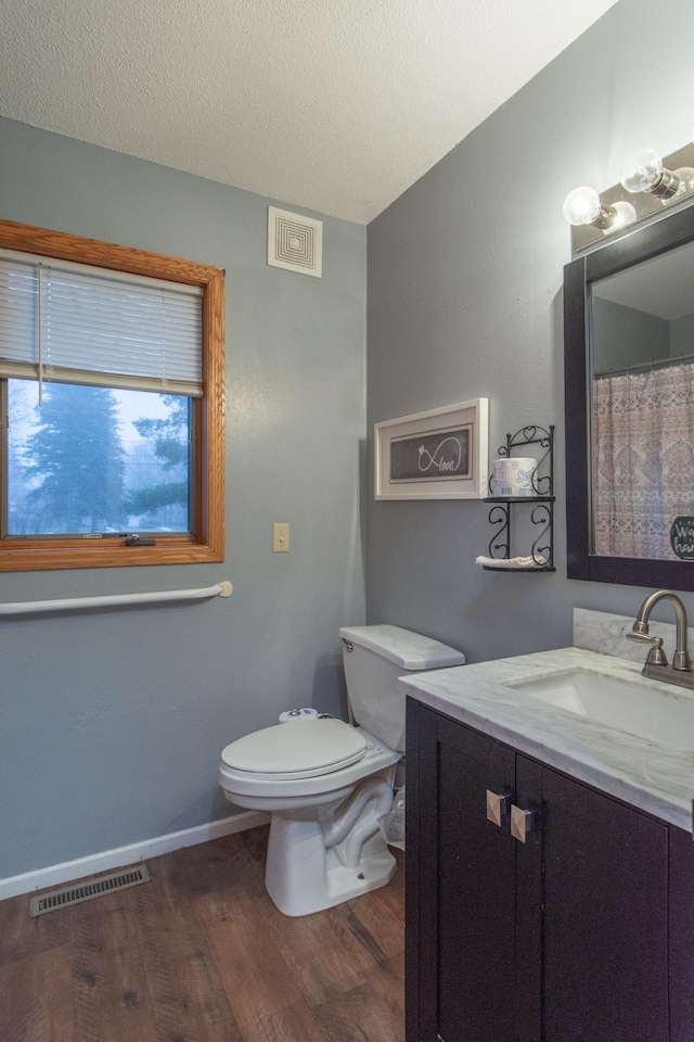 bathroom with hardwood / wood-style floors, vanity, toilet, and a textured ceiling