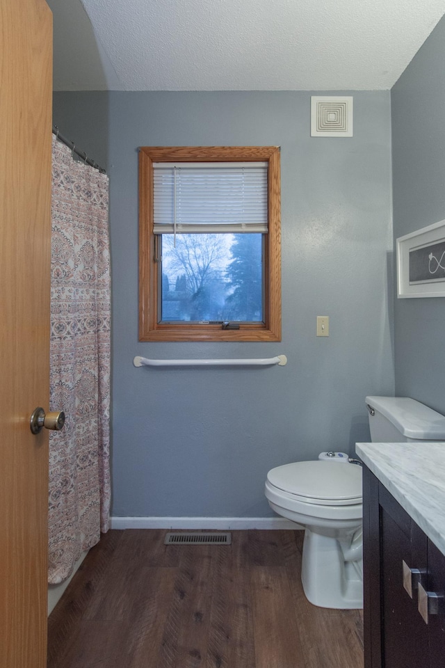 bathroom featuring hardwood / wood-style floors, vanity, toilet, and a textured ceiling