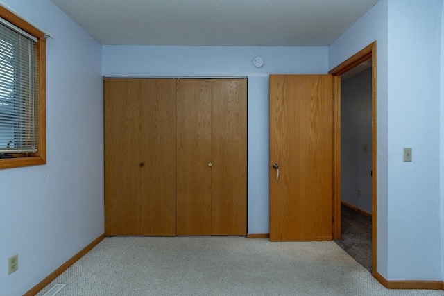 unfurnished bedroom with a closet and light colored carpet