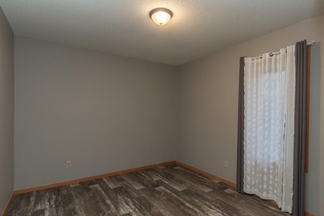 spare room with a textured ceiling and dark wood-type flooring