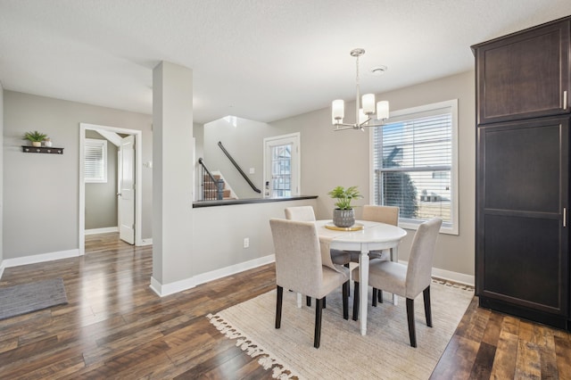 dining space with dark hardwood / wood-style flooring and an inviting chandelier