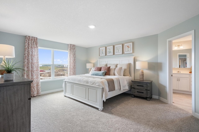 bedroom with sink, connected bathroom, and light colored carpet