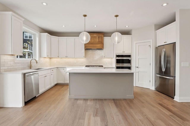 kitchen featuring stainless steel appliances, sink, decorative light fixtures, a center island, and white cabinetry