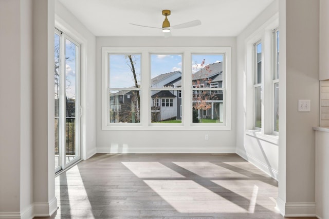 unfurnished sunroom featuring ceiling fan and a healthy amount of sunlight