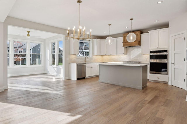 kitchen featuring a center island, stainless steel appliances, white cabinetry, and hanging light fixtures