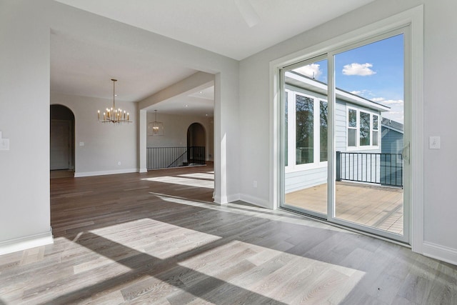 unfurnished room with hardwood / wood-style floors and a notable chandelier