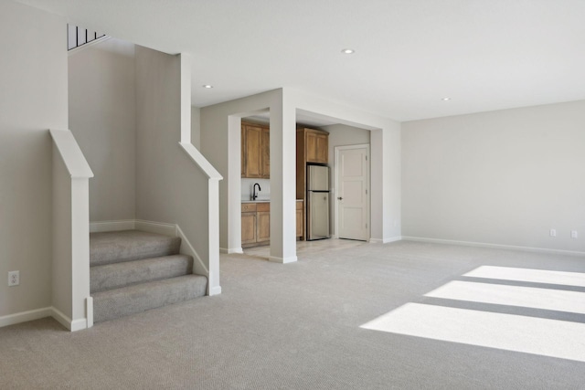 interior space with light colored carpet, sink, and stainless steel refrigerator