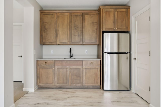 kitchen featuring stainless steel refrigerator, sink, and light hardwood / wood-style flooring