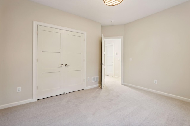 unfurnished bedroom with light carpet and a closet