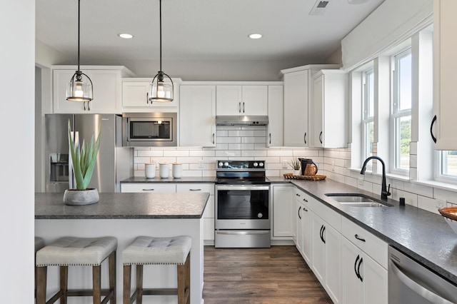 kitchen with sink, hanging light fixtures, dark wood-type flooring, white cabinets, and appliances with stainless steel finishes