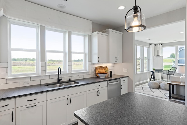 kitchen featuring backsplash, sink, pendant lighting, dishwasher, and white cabinetry