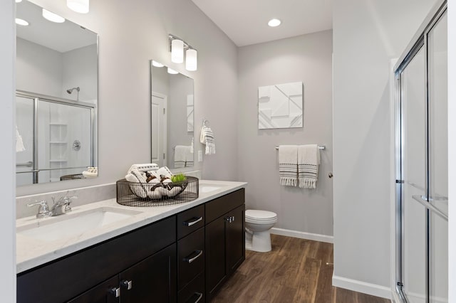 bathroom with vanity, wood-type flooring, a shower with shower door, and toilet