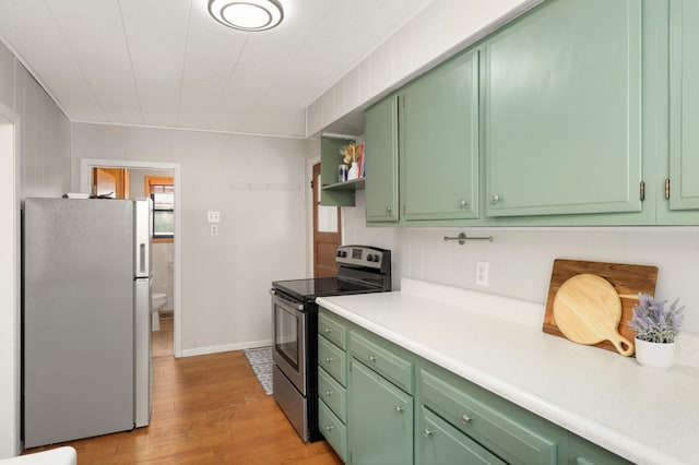 kitchen featuring appliances with stainless steel finishes, light wood-type flooring, light countertops, and green cabinets