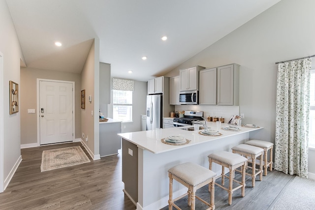 kitchen with kitchen peninsula, appliances with stainless steel finishes, vaulted ceiling, and a kitchen breakfast bar