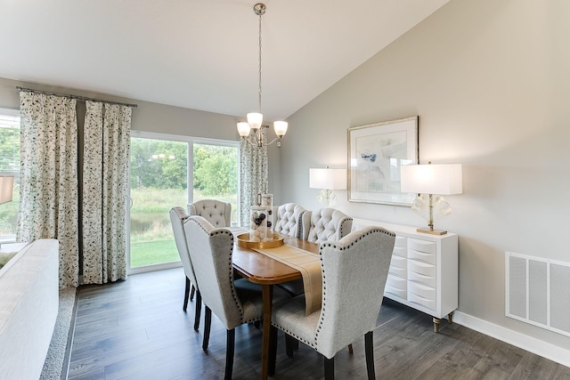 dining area with dark hardwood / wood-style floors, an inviting chandelier, and vaulted ceiling