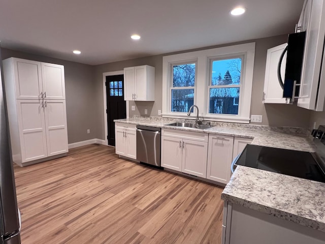 kitchen featuring white cabinetry, dishwasher, sink, light hardwood / wood-style flooring, and range