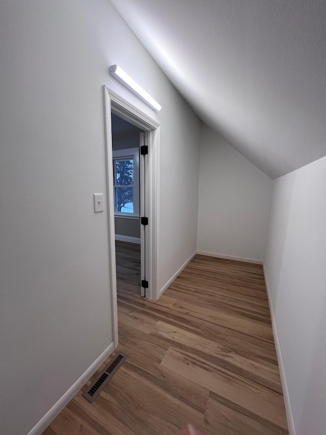 hallway featuring vaulted ceiling and light hardwood / wood-style flooring