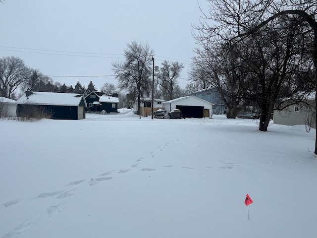 yard covered in snow featuring a garage and an outdoor structure